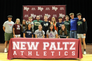Graduating athletes posing together in front of NP banner